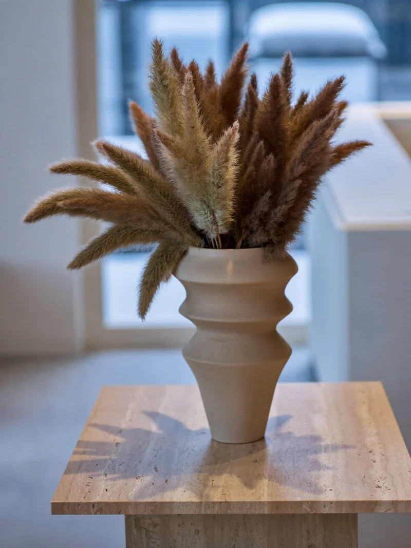 Vaso in argilla opaca con pampas secca su un tavolino in travertino